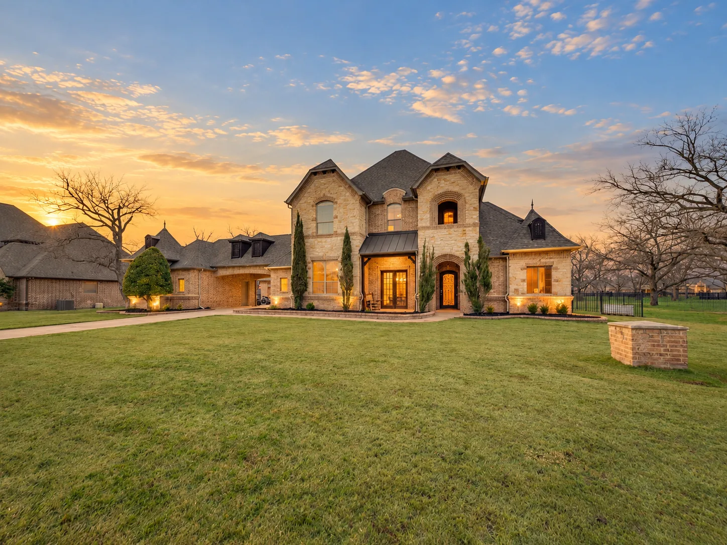 Two-story stone and brick home in The Orchards on Eagle Mountain Lake, set on a wide lawn at sunset